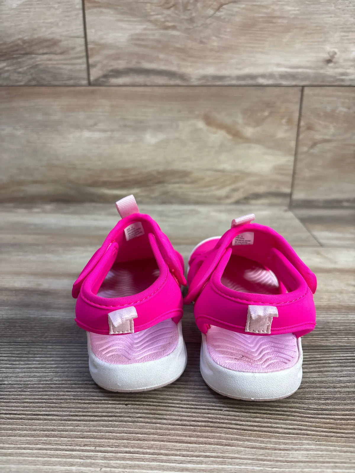 Front view of pink Cat and Jack Speedo water shoes showcasing hook and loop closures with white soles on a wood look floor