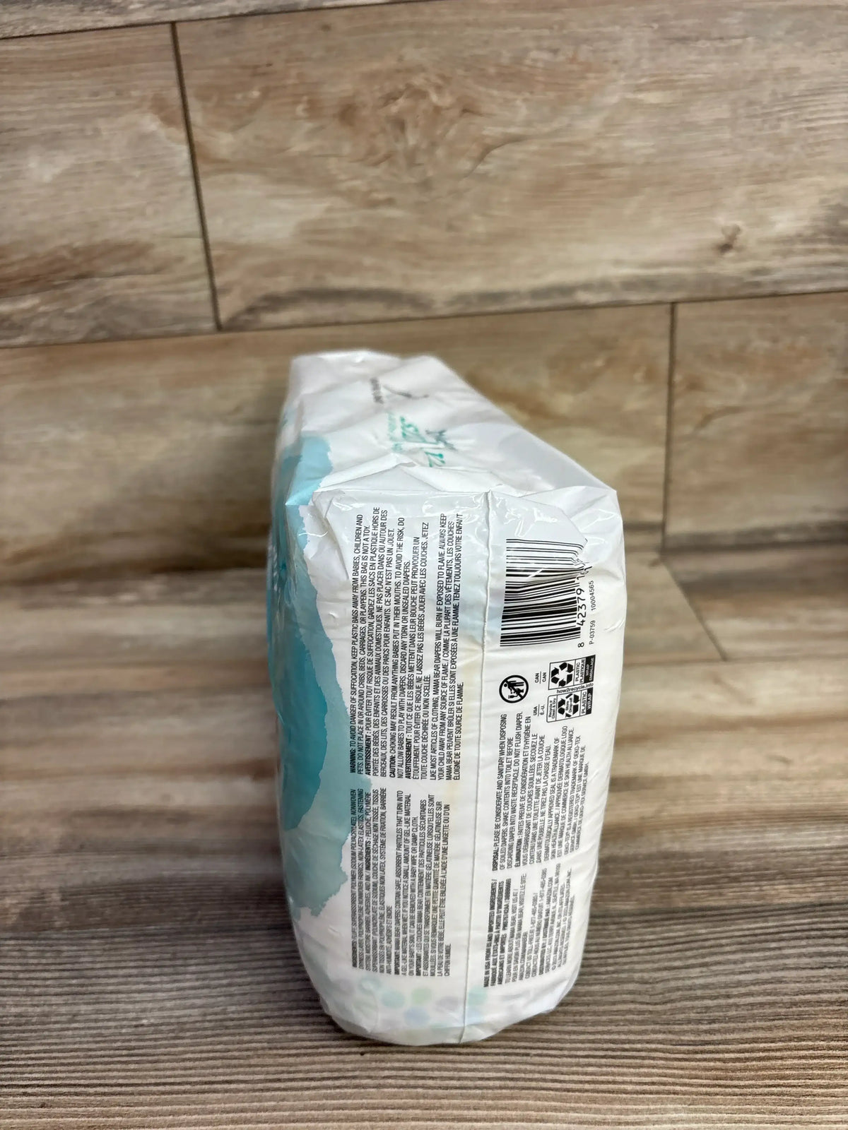 Side view of NEW Mama Bear Gentle Touch Diapers Size 1 pack showing sealed packaging and barcode on wood floor background