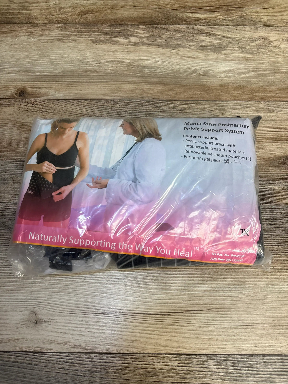 Packaged postpartum pelvic support system with contents listed, placed on wood floor