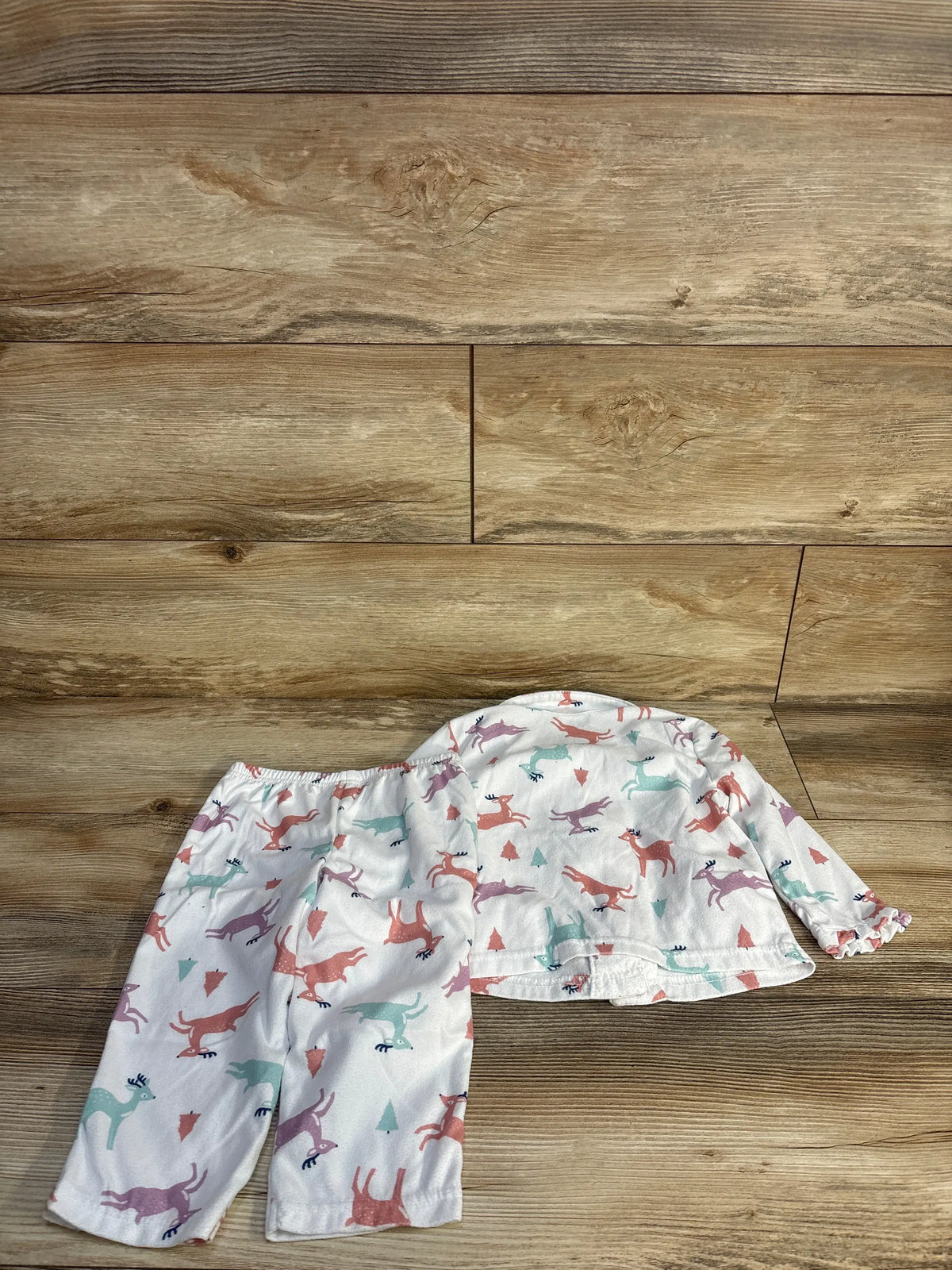 Front view of white toddler two-piece button-up shirt and elastic-waist pants set with pastel deer print laid flat on wood background