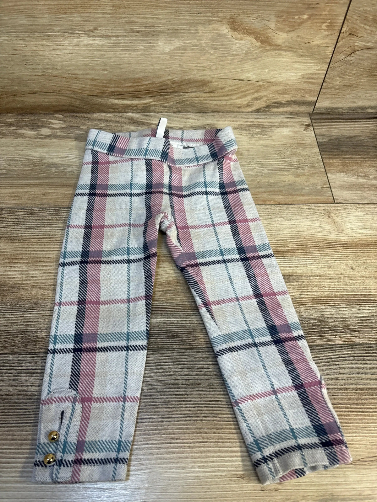 Girls plaid leggings with pink and navy check pattern and gold button details on cuffs