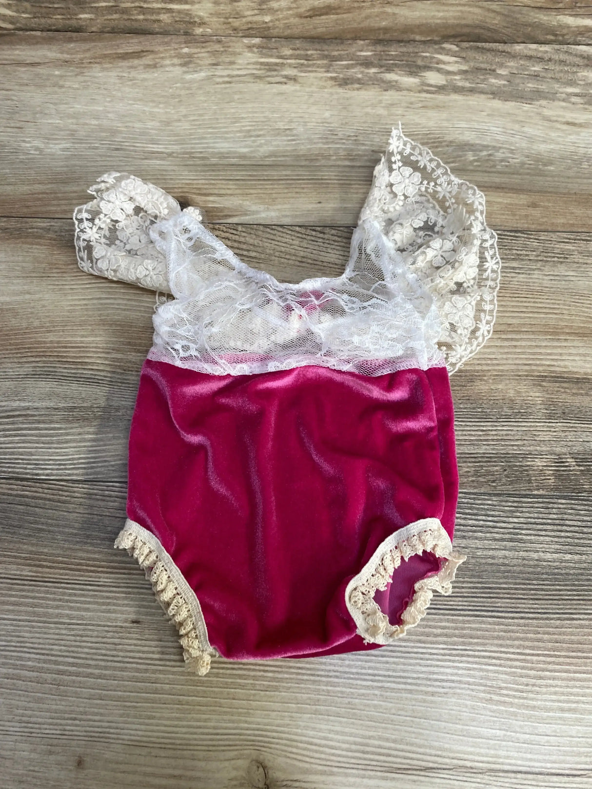 Front view of newborn white velvet romper with pink lace trim and bow, showing puff sleeves on plain white background
