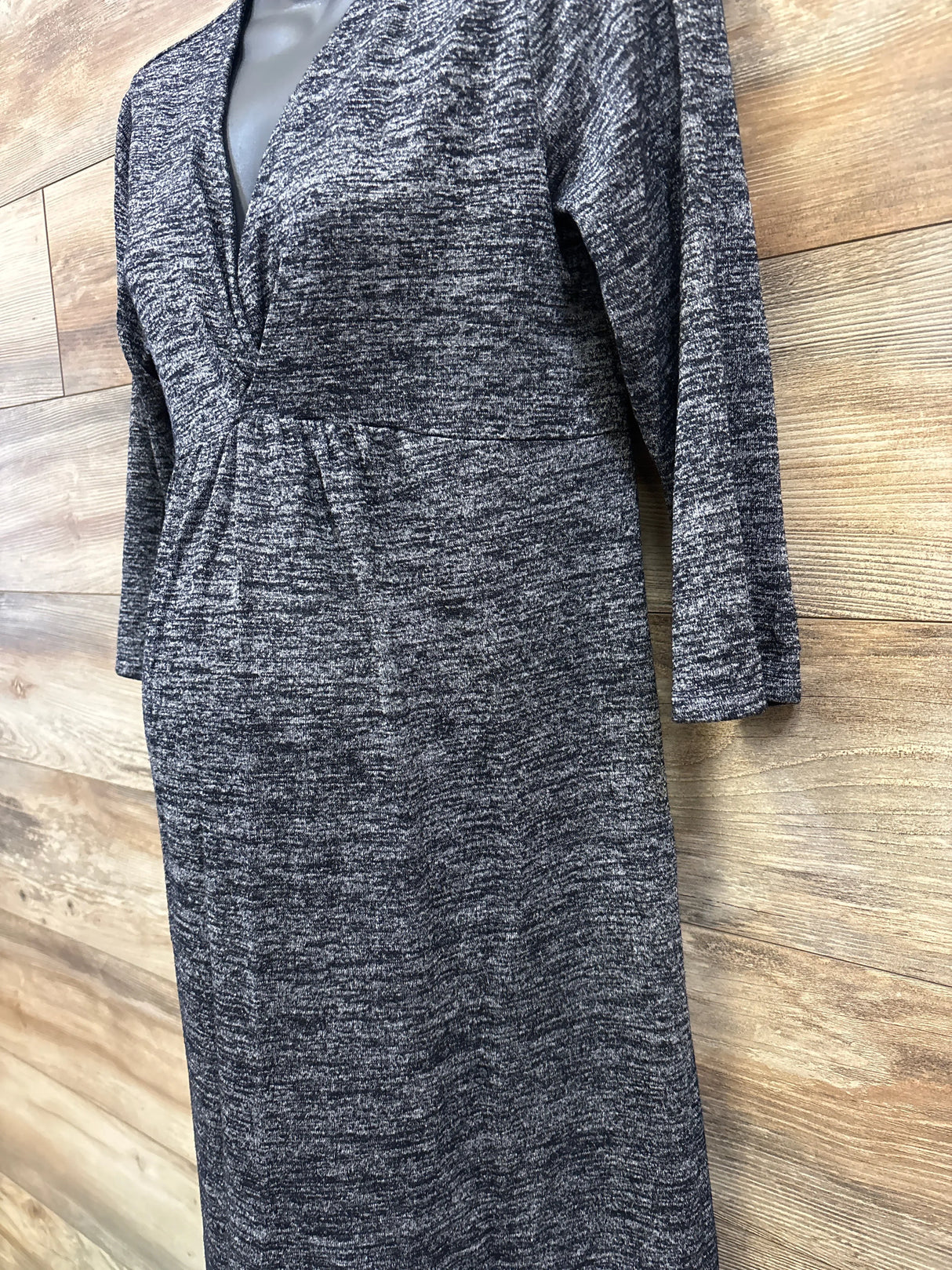 Close-up front view of Gap Maternity V-Neck dress in black showing heathered texture, V-neck and empire waist against wood background