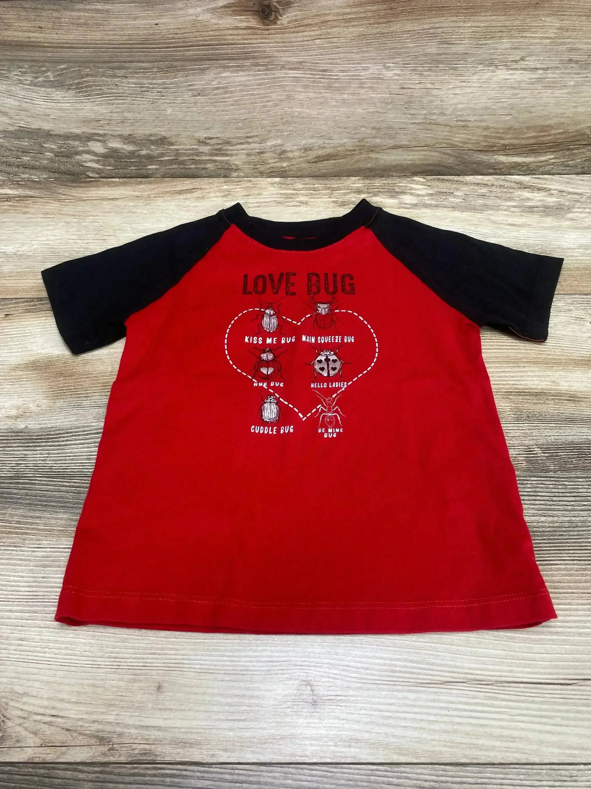 Front view of toddler raglan shirt in black with red sleeves showing Celebrate Love Bug ladybug graphic on white background