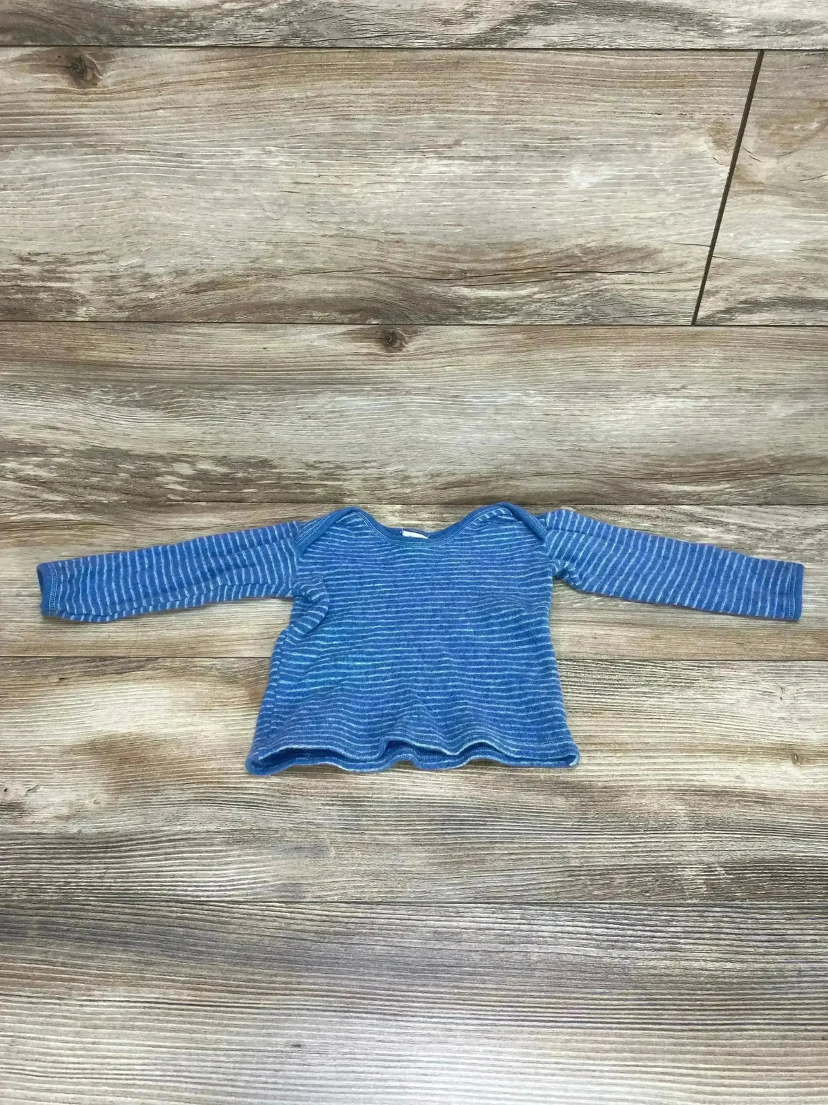 Front view of baby blue striped wool shirt size 9-12 months showcasing long sleeves and envelope neckline on wood floor background