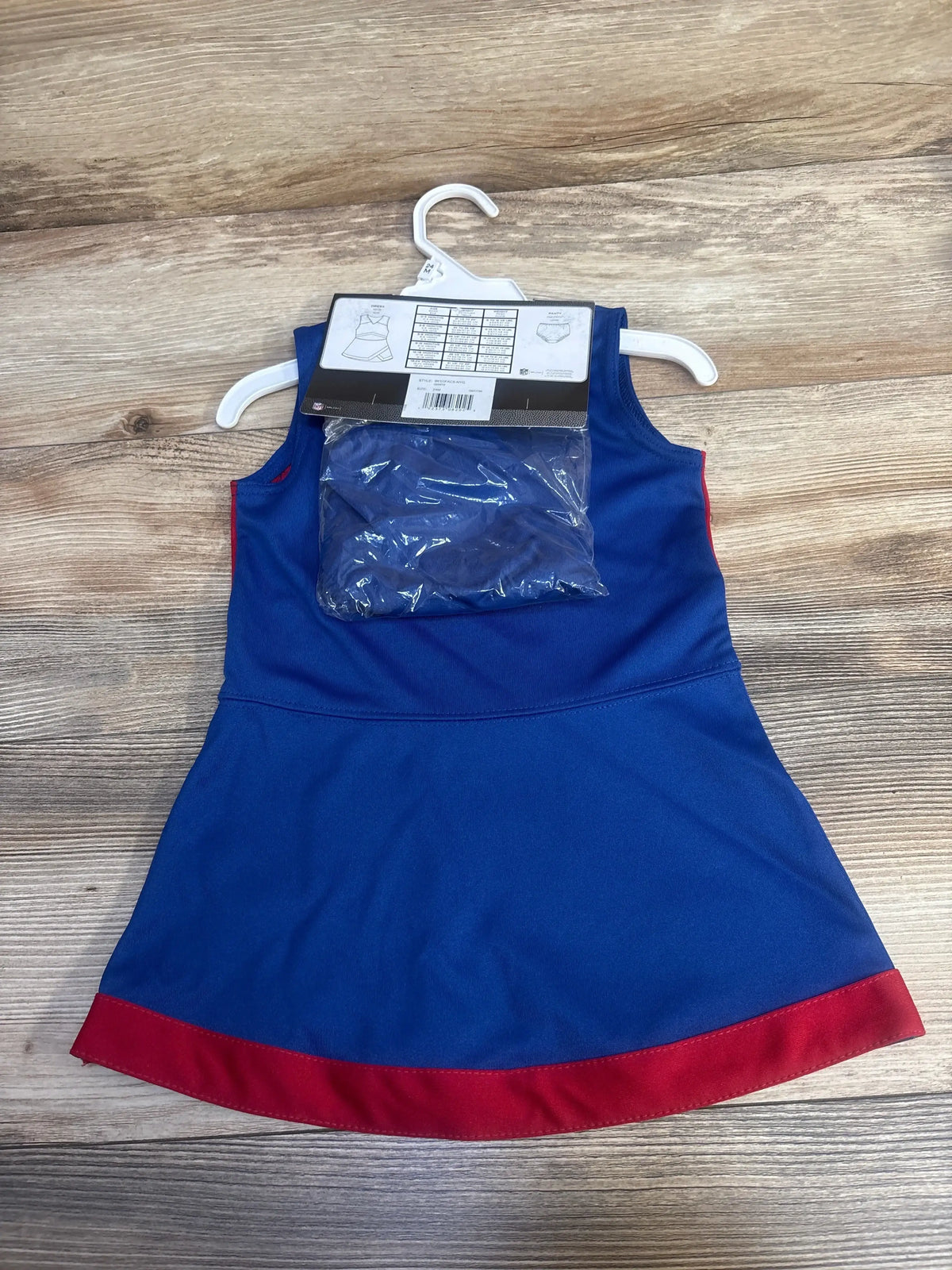 Blue sleeveless dress with red hem for toddler, displayed on white plastic hanger on wooden surface