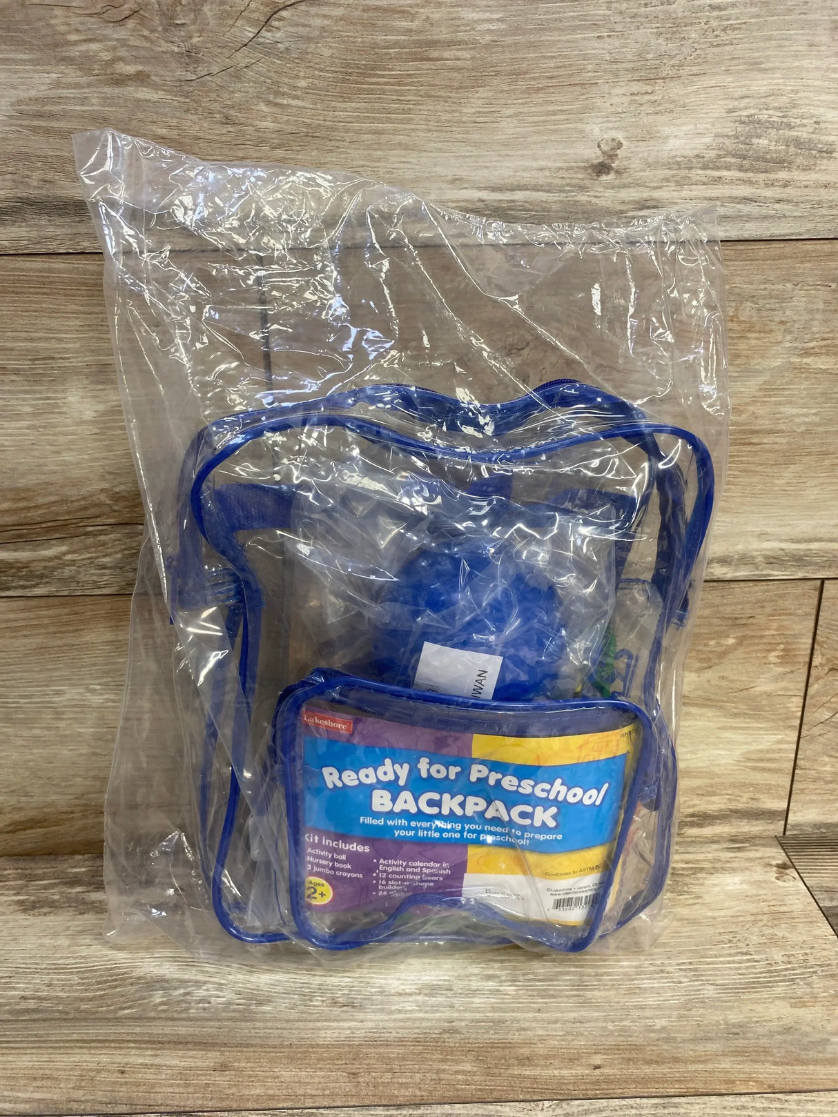Front of Lakeshore Ready for Preschool backpack in clear packaging showing label Ready for Preschool BACKPACK on wood floor