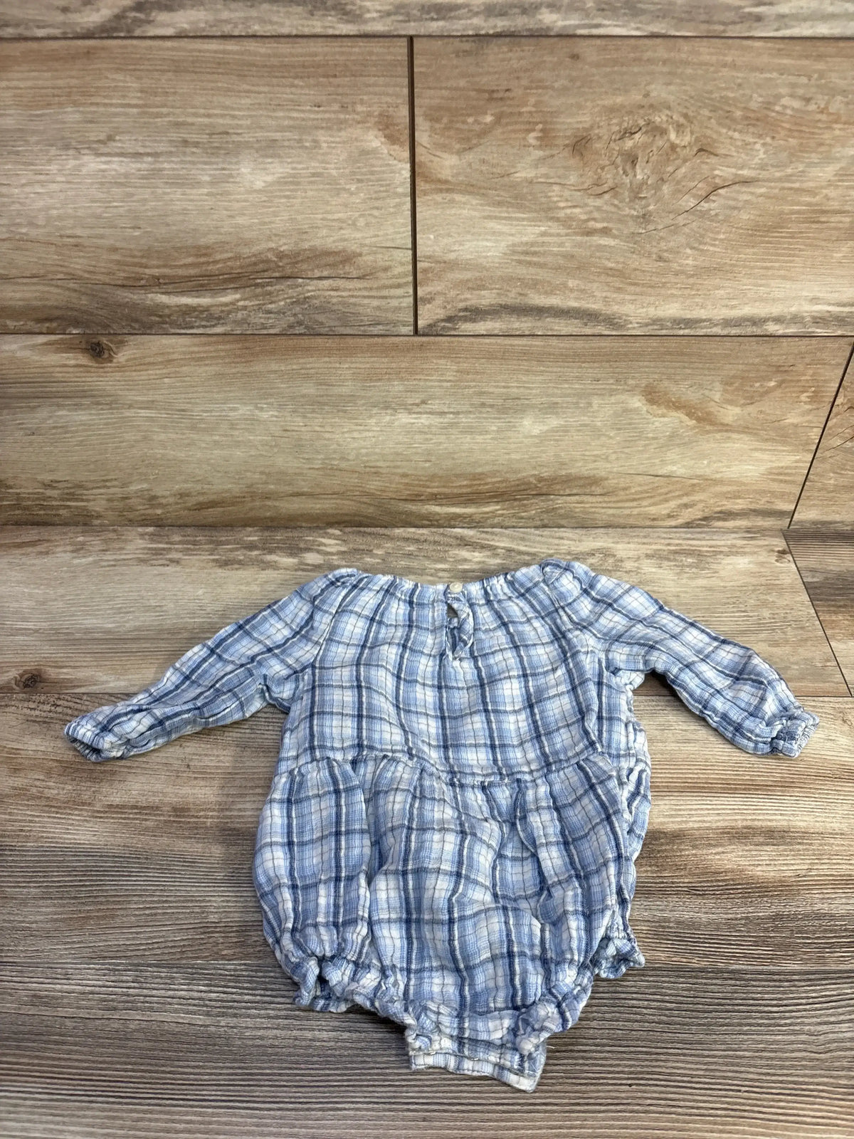 Flat lay of blue plaid Old Navy bubble romper with long sleeves, gathered waist and elasticized legs on wood background