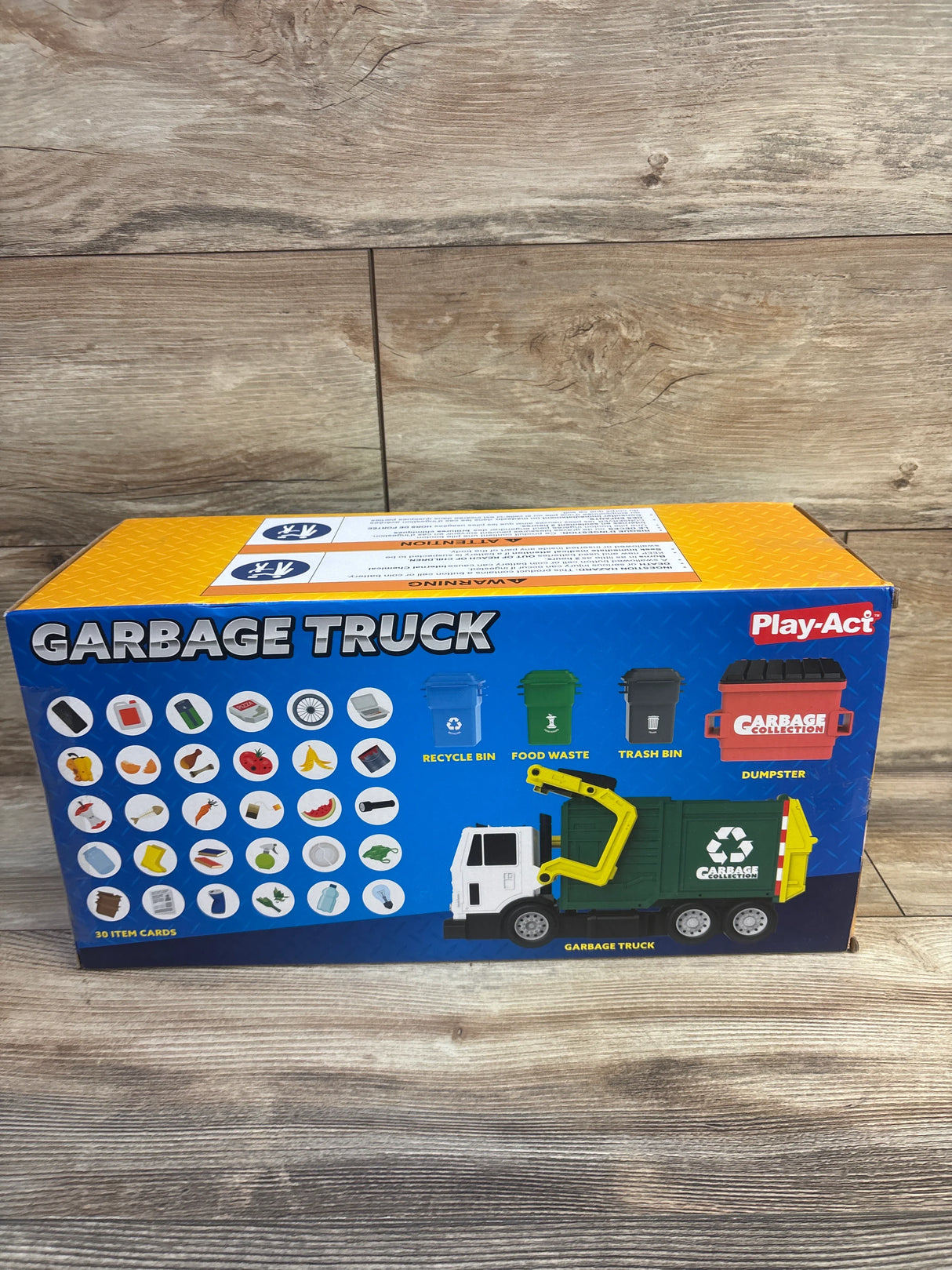 Front view of Play-Act 16-inch garbage truck box showing green truck with lifting arm and recycling icons on wood floor