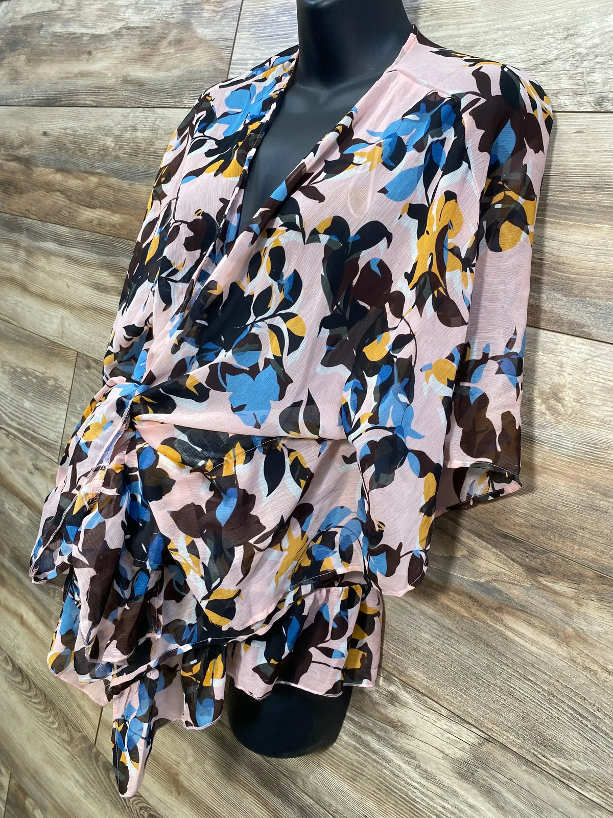 Front view of a pink floral open front maternity kimono on a black mannequin, showing blue, yellow, and dark floral print