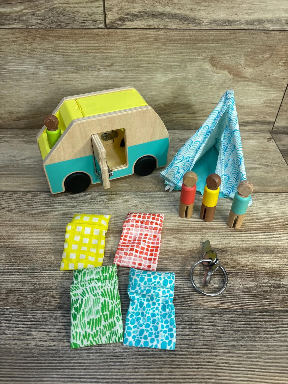 Wooden camper van toy with family figures, fabric tent, and patterned bedding for kids' imaginative play.