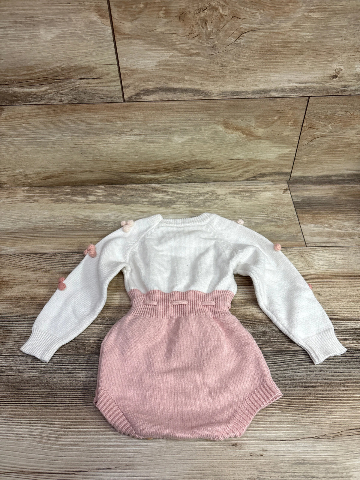 Front view of ZZLBUF Pom-Pom Heart Knit Bubble Romper with white knit top and pink bottom on a wood floor