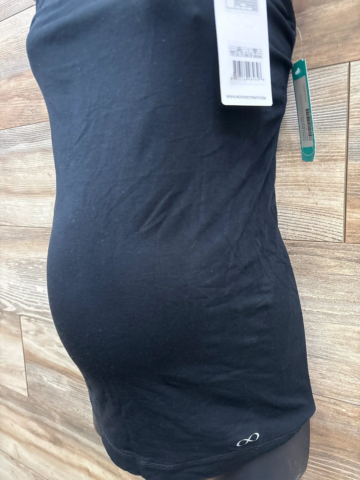 Black maternity tank top on mannequin with tags against wood plank background at kids resale store