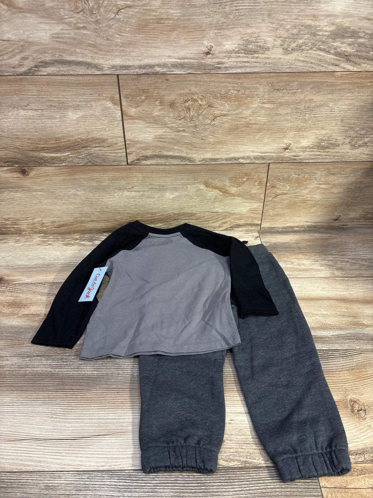 Top view of Cat & Jack Boo shirt and joggers set showing a gray shirt with black raglan sleeves and charcoal joggers on wood flooring