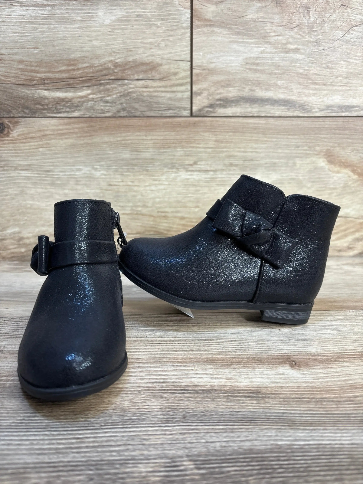 Black toddler ankle boots with bow detail on wooden background