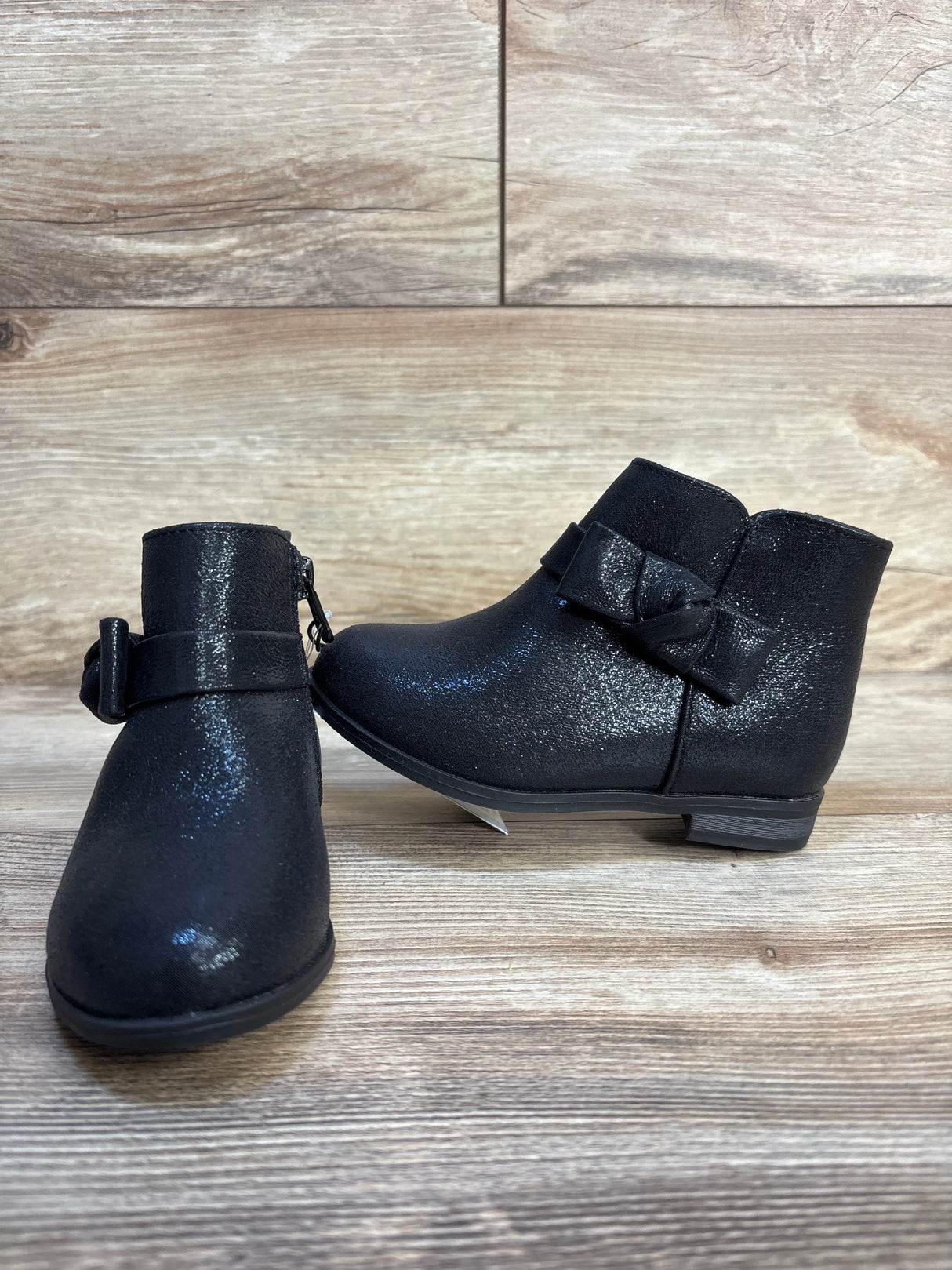 Black toddler ankle boots with bow detail on wooden background