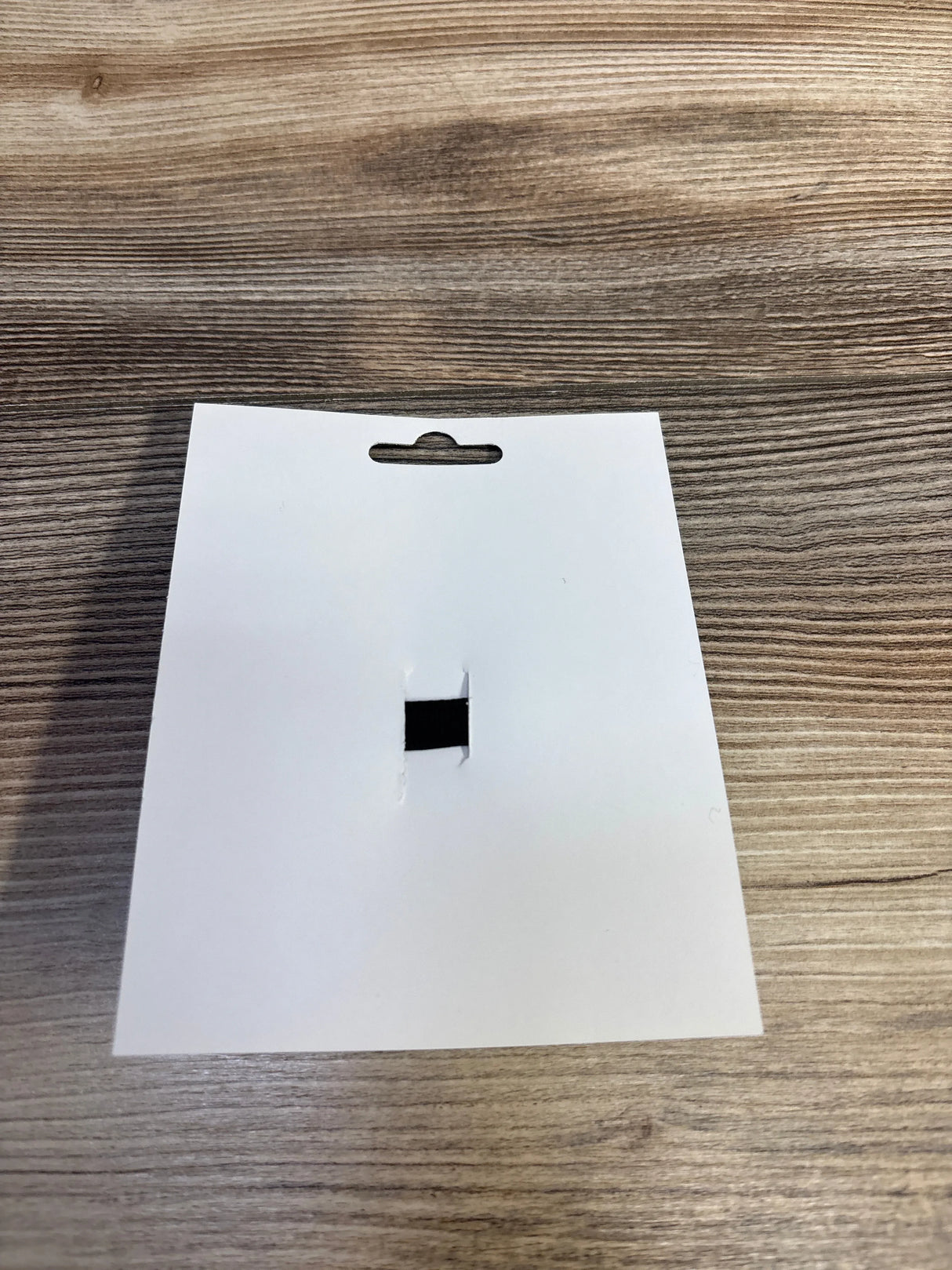 Blank white product tag with hang hole on wood surface, for kids and maternity items