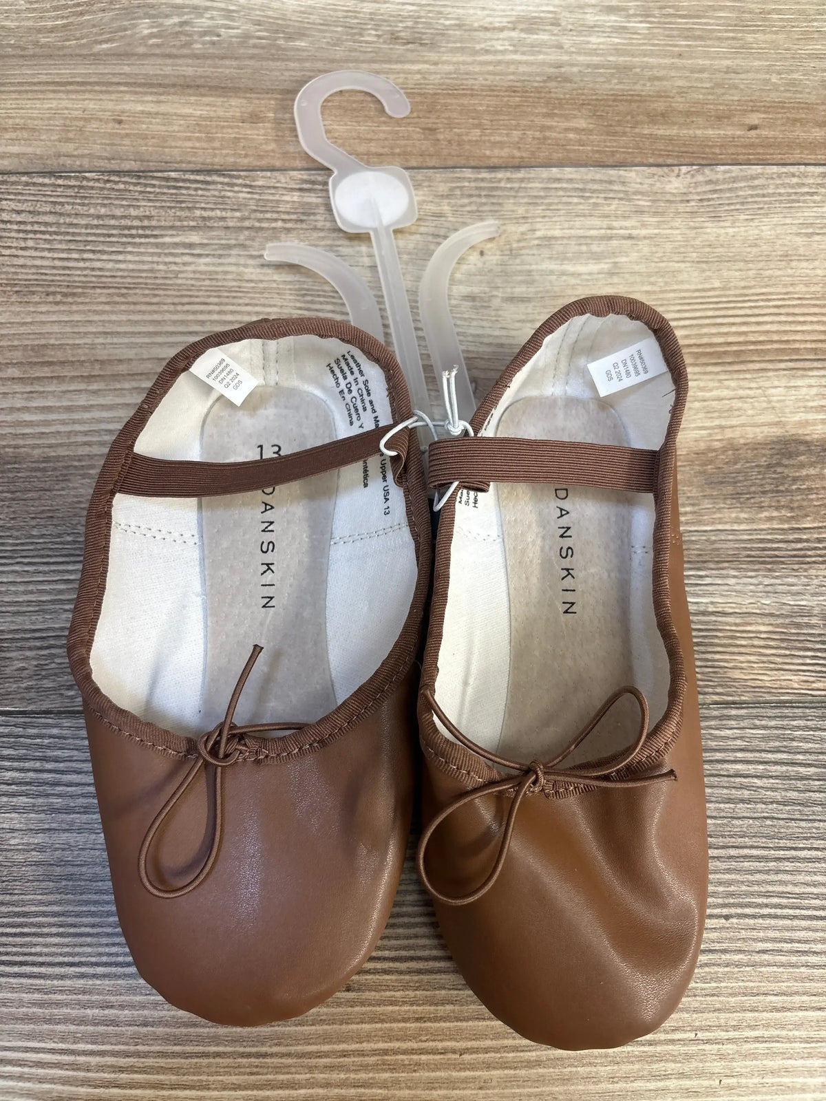 Brown Danskin toddler ballet flats with bows, size 13, on wooden background