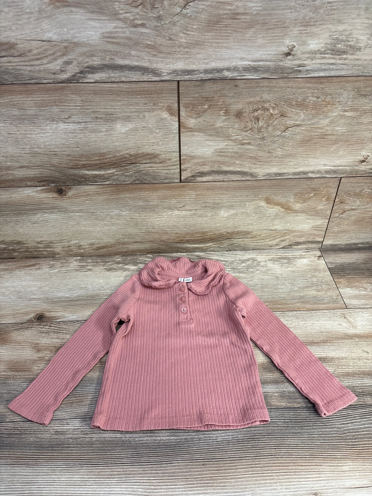 Pink ribbed long-sleeve toddler top with peter pan collar and buttons on wooden floor