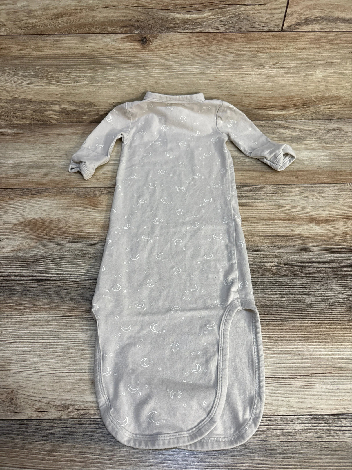 Light gray baby sleep gown with crescent moon and star pattern on wood background