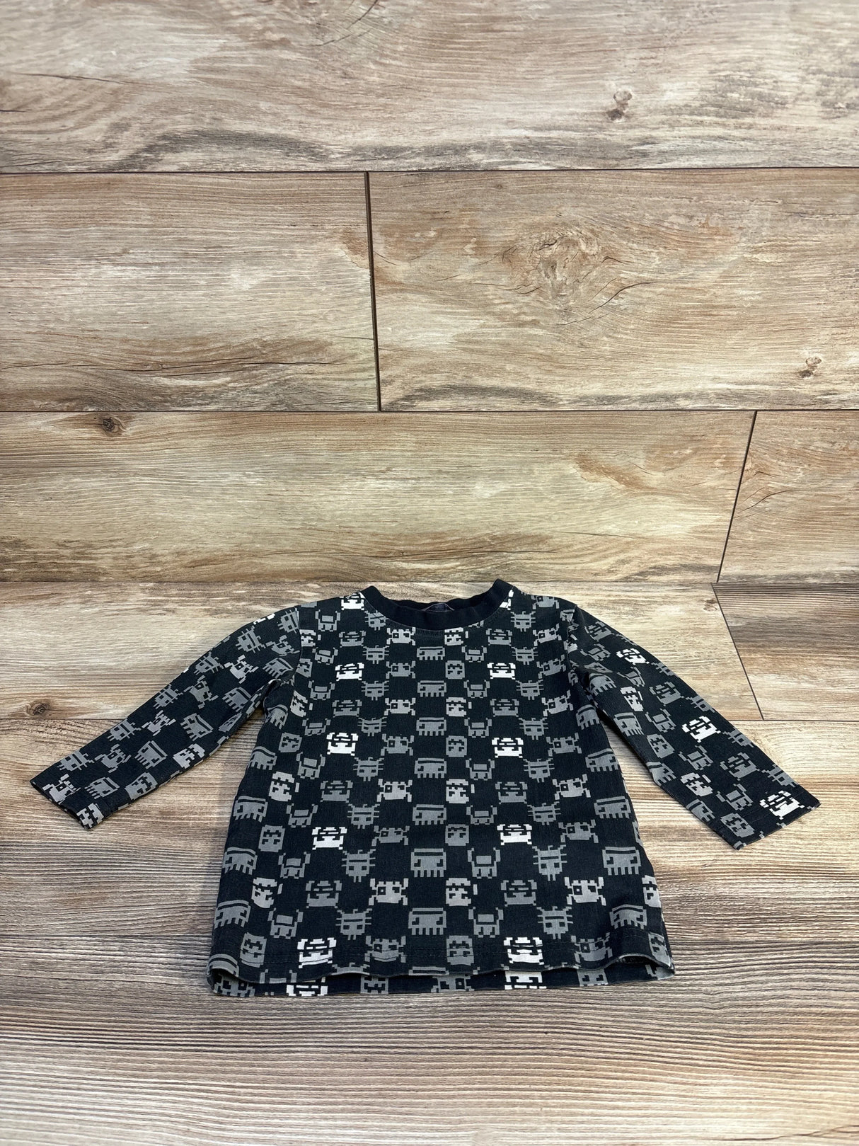 Long sleeve black toddler shirt with gray pixel animal pattern on wood floor