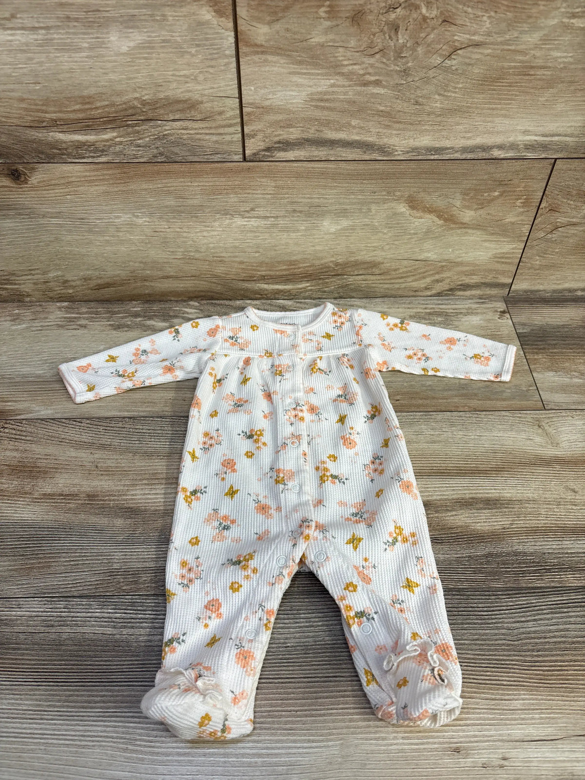 Carter's cream floral waffle knit snap sleeper for baby size 3m on a wooden background