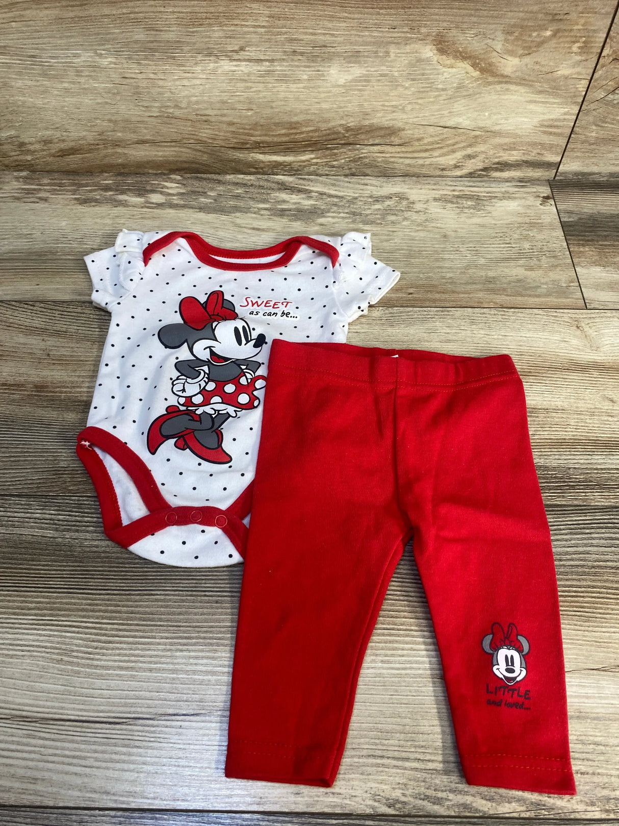 Minnie Mouse baby girl outfit with polka dot onesie and red leggings on wood background