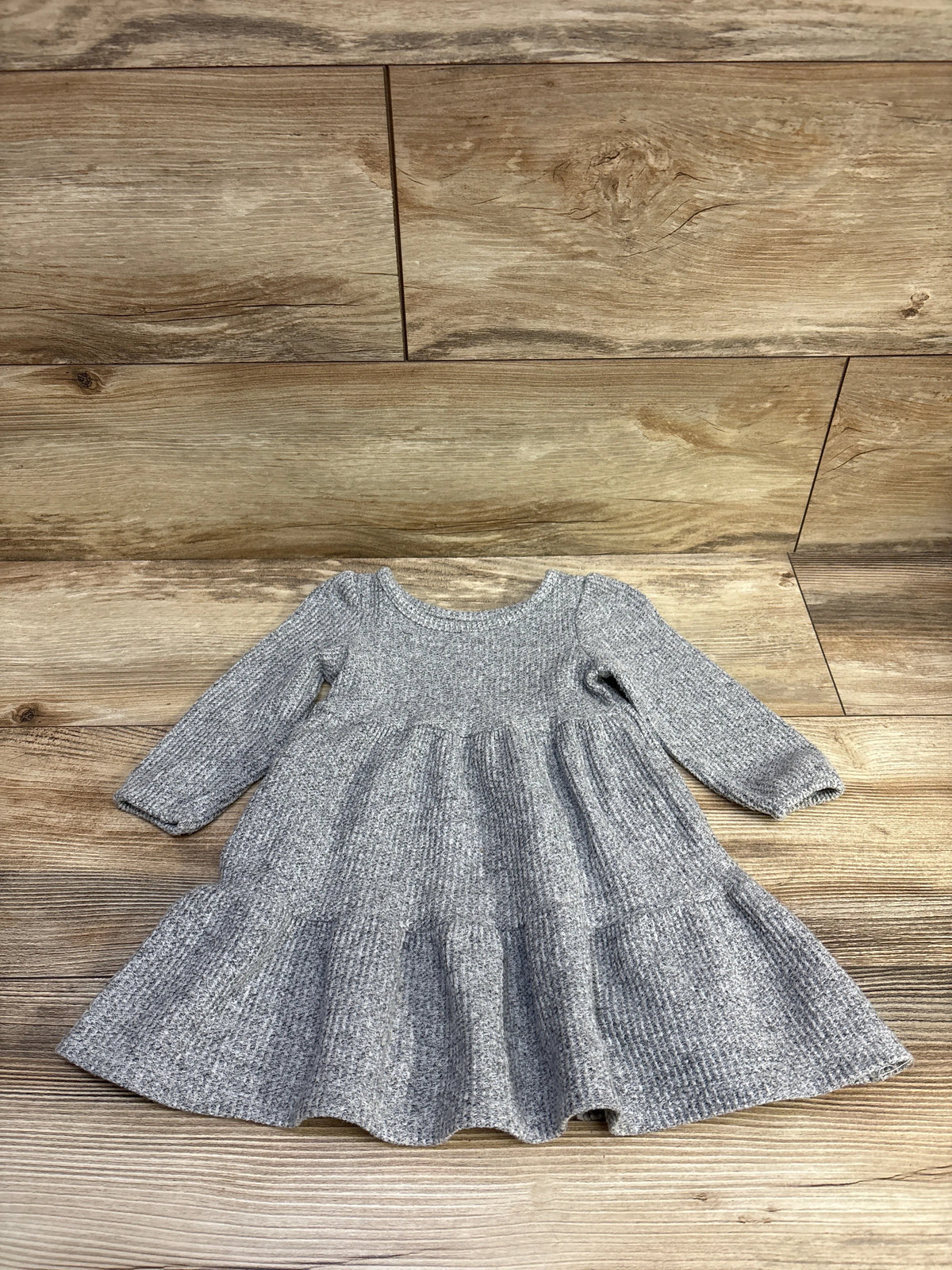 Front view of Cat & Jack knit long-sleeve dress in grey, size 12 months, showing gathered waist and tiered skirt on wood