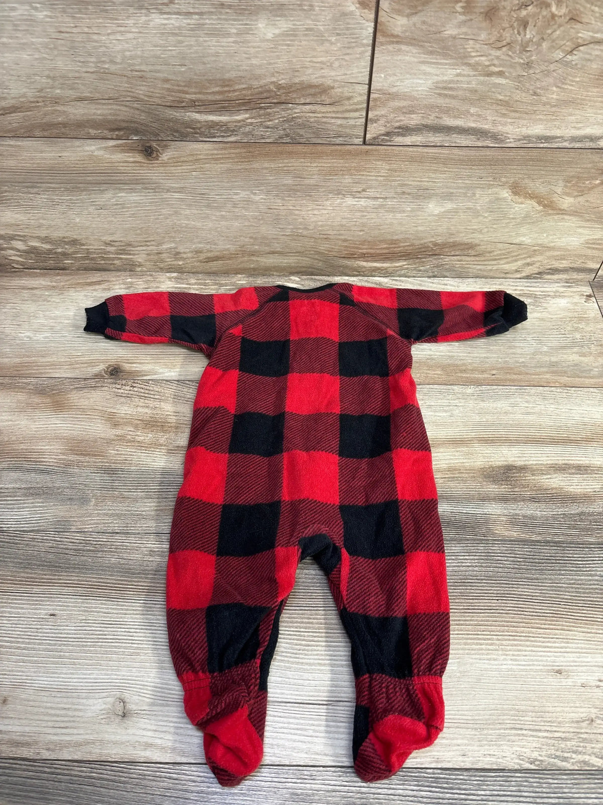 Red and black buffalo plaid footed baby pajamas on wooden floor for kids
