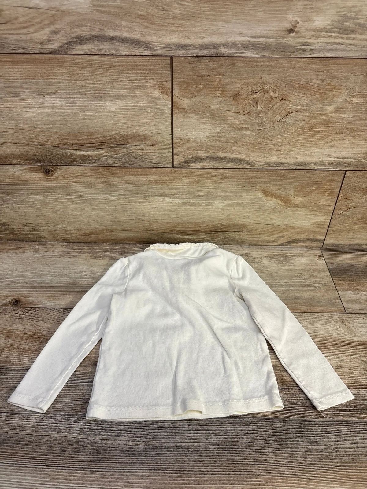 Back view of Gymboree long sleeve Peter Pan collar top in cream size 3T showcasing ruffle collar trim on wood plank floor
