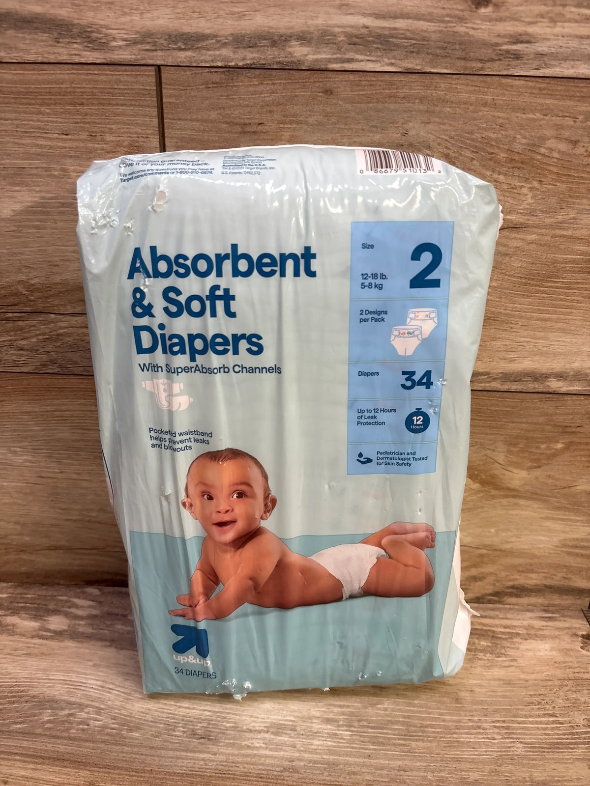 Front view of up&up absorbent and soft diapers, size 2, 34-pack, showing 12-hour leak protection on wood