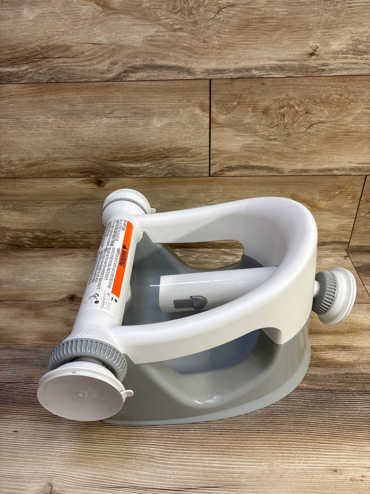 Angled top-down view of Summer Infant My Bath Seat, grey, showing contoured seat and suction-cup feet on wood background