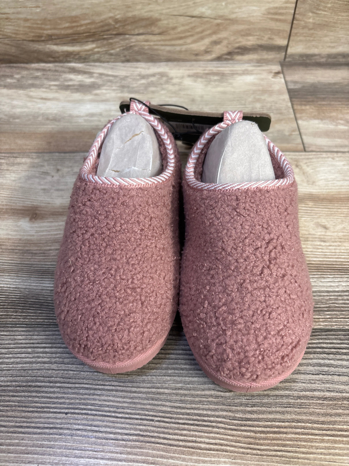 Front view of Pawz toddler cozy slippers showcasing pink sherpa texture and striped trim on wood-look floor