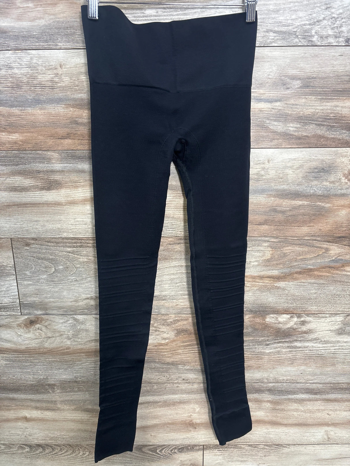 Black high-waisted maternity leggings on wood background
