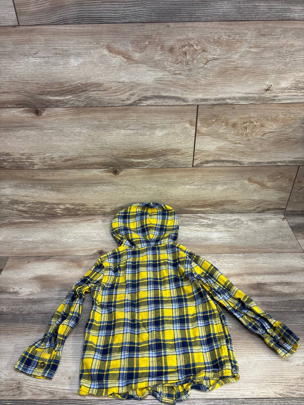 Yellow and blue plaid hooded flannel shirt for kids on wood background