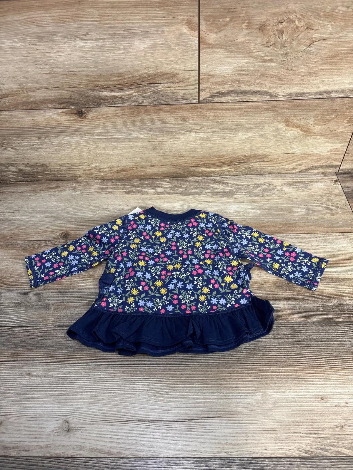 Navy blue floral long sleeve baby dress with ruffle hem on wood floor background