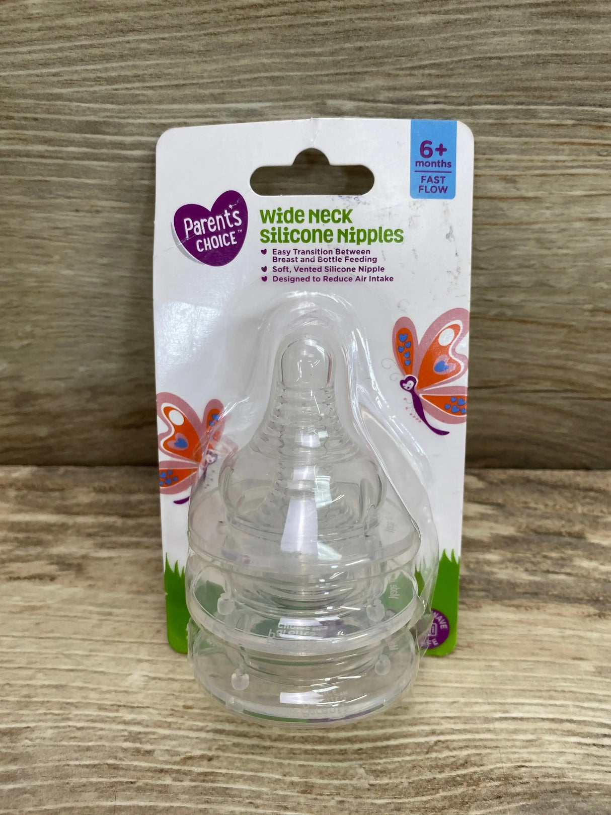 Front view of Parent’s Choice wide-neck silicone nipples 3-pack, stacked clear nipples with 6+ months label on wood