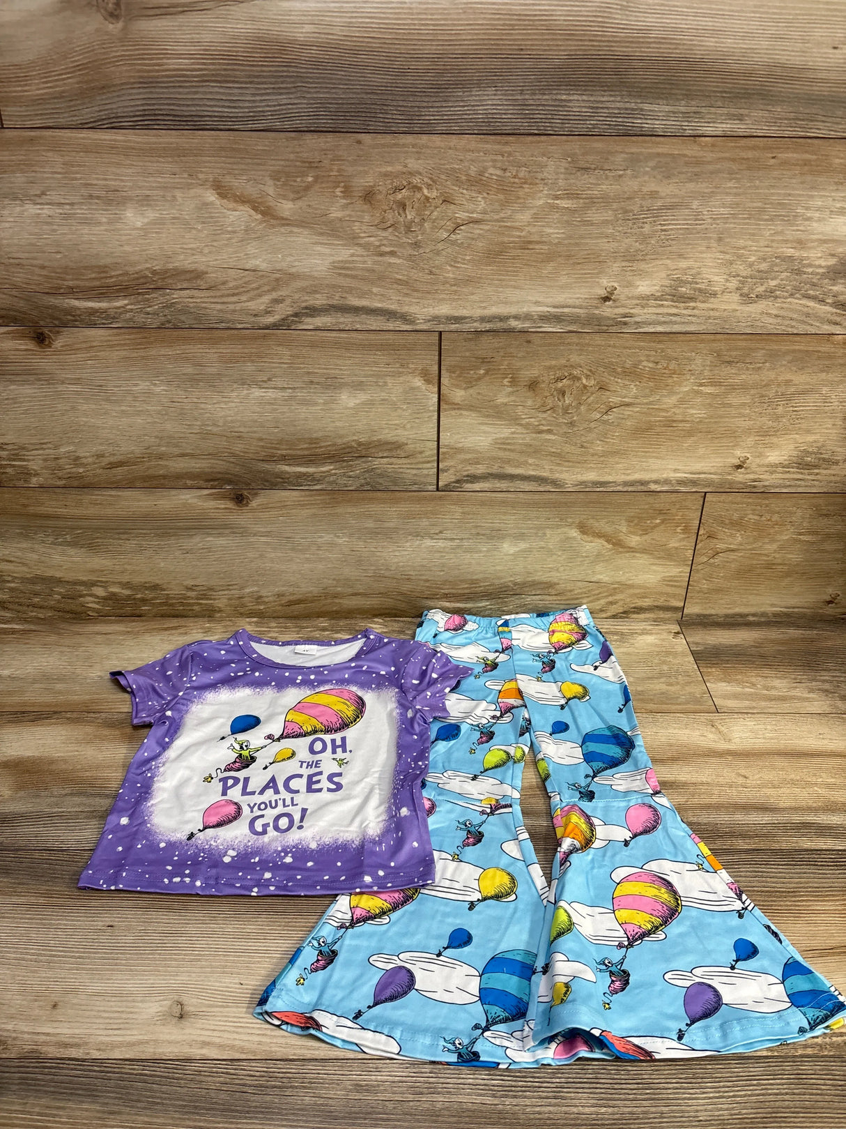 Flat lay of Dr. Seuss 2pc set showing purple tee reading Oh, The Places You’ll Go! and blue bell-bottom pants