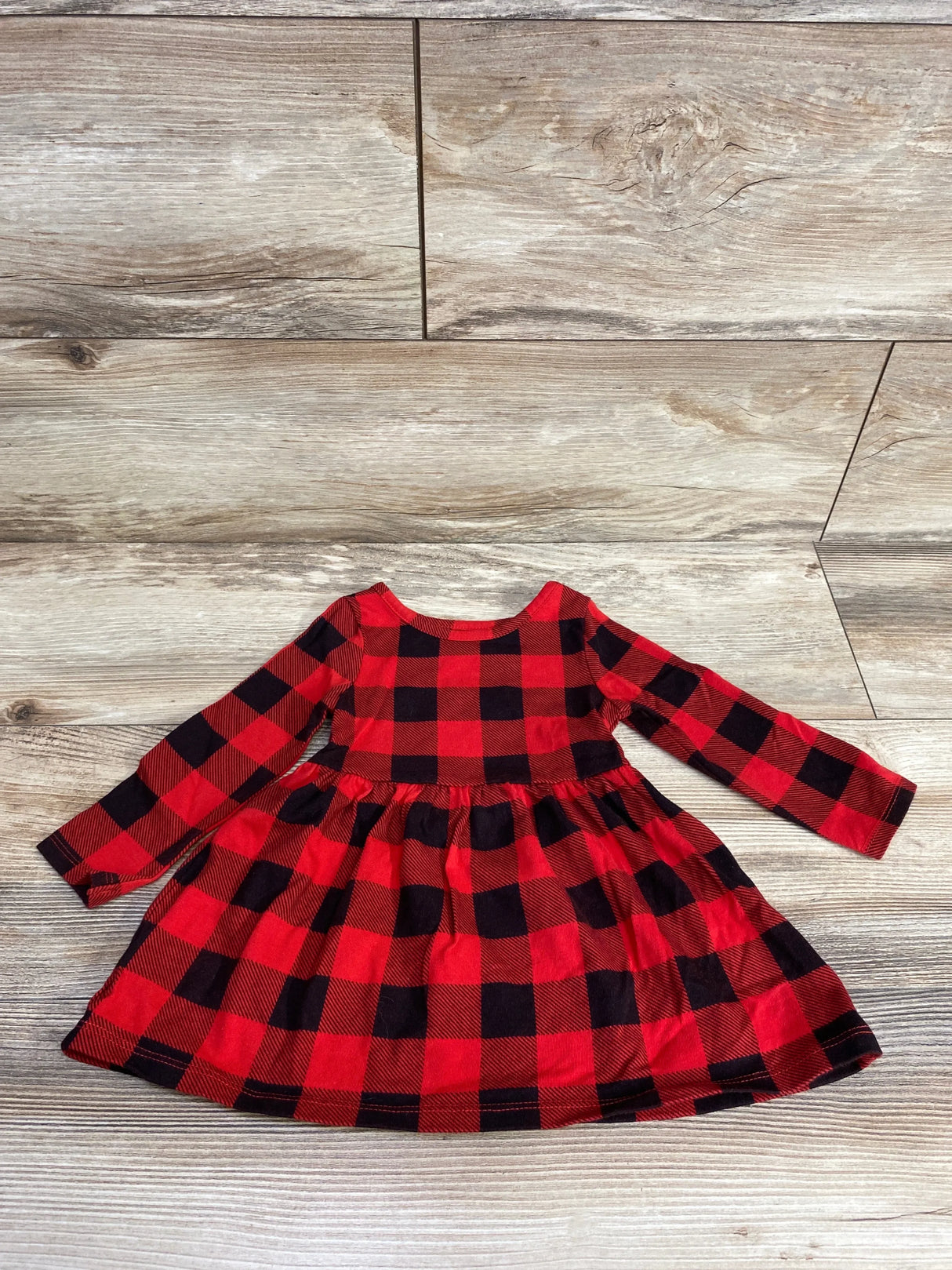 Red and black buffalo plaid long-sleeve toddler dress on wood floor background