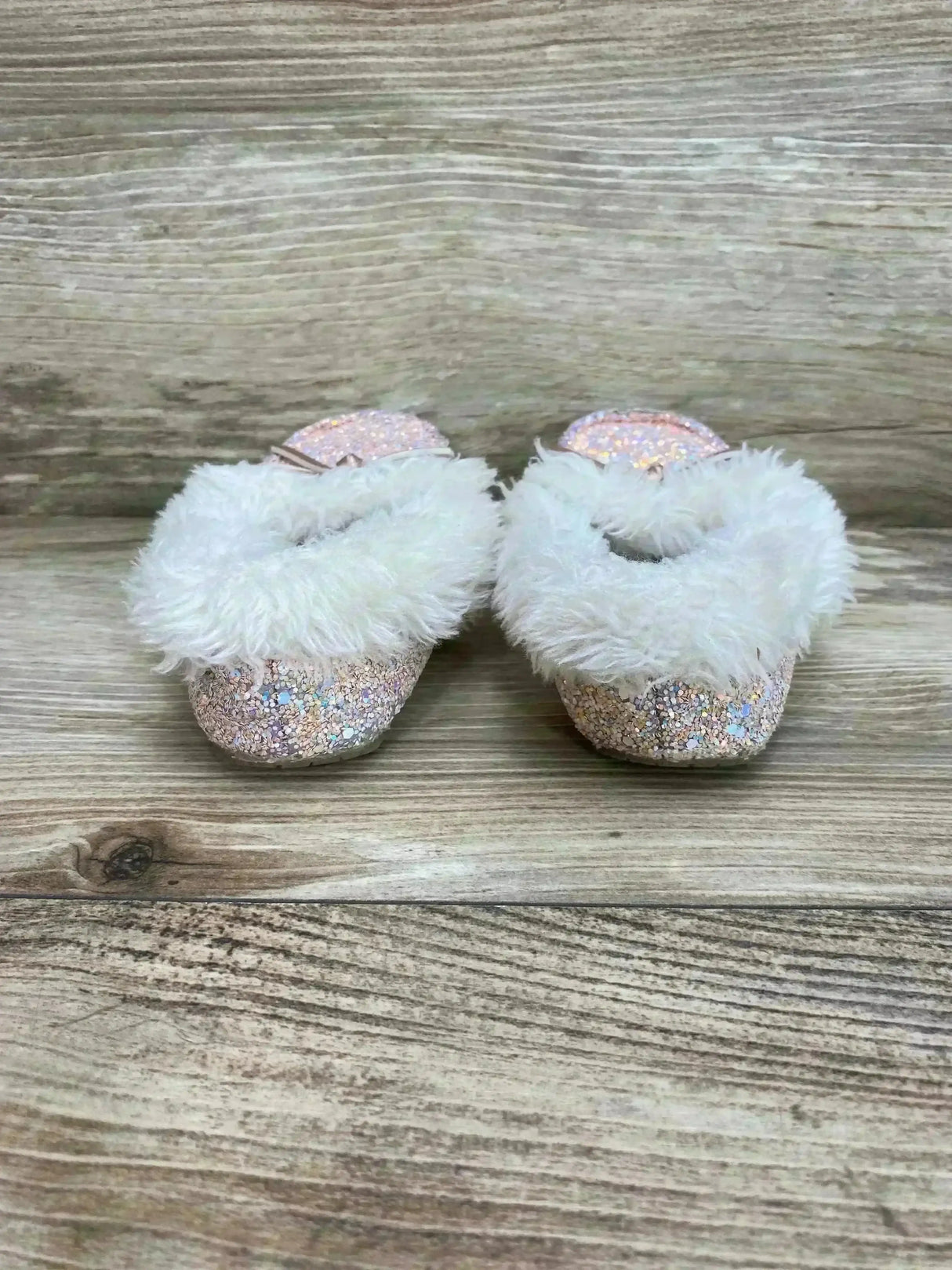 Front view of Cat & Jack Medora toddler slippers showcasing pink glitter finish and white faux fur trim on wood background