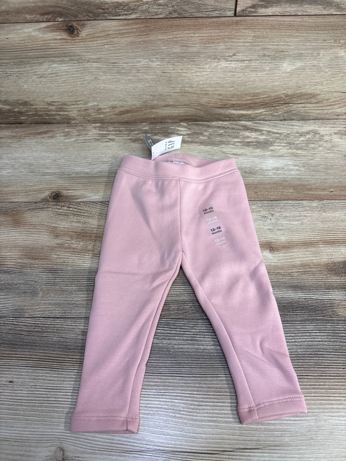 Pink baby leggings, size 12-18 months, laid flat on wood floor, new with tag