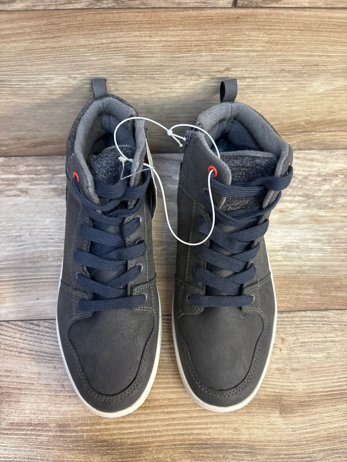 Pair of dark gray kids' high-top sneakers with navy laces on wood floor