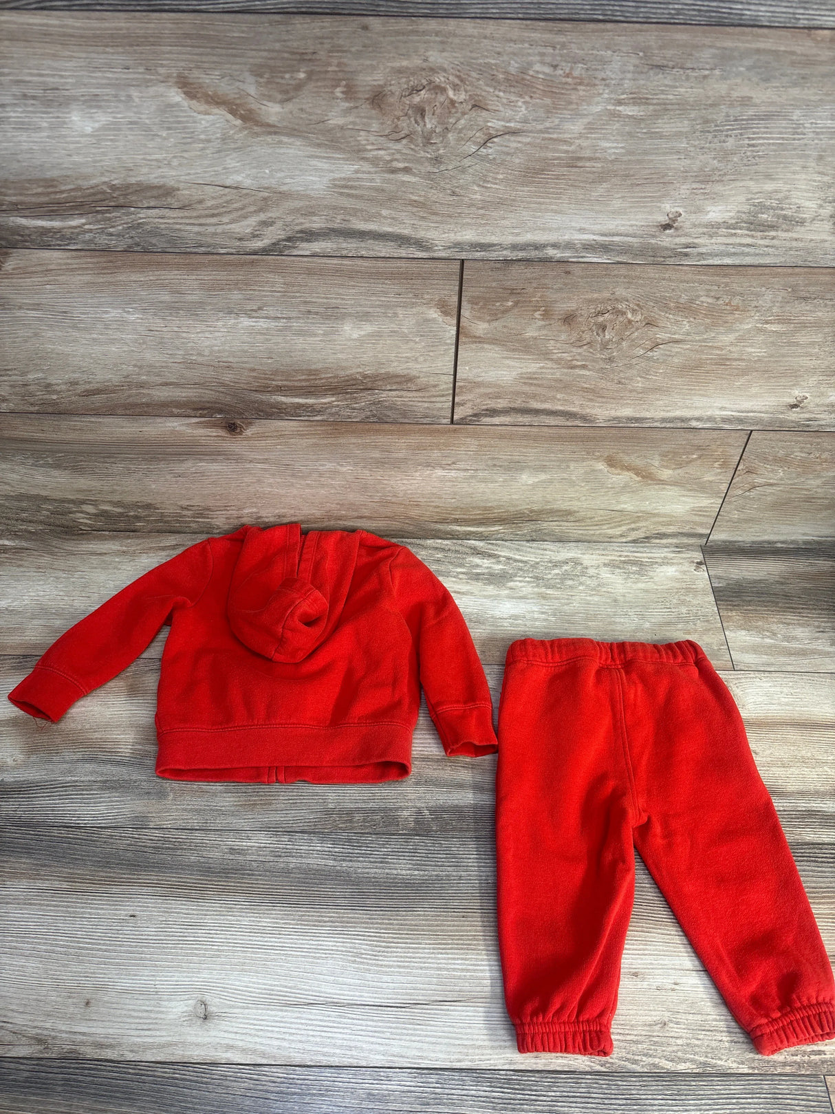Red toddler hoodie and sweatpants set on wooden floor