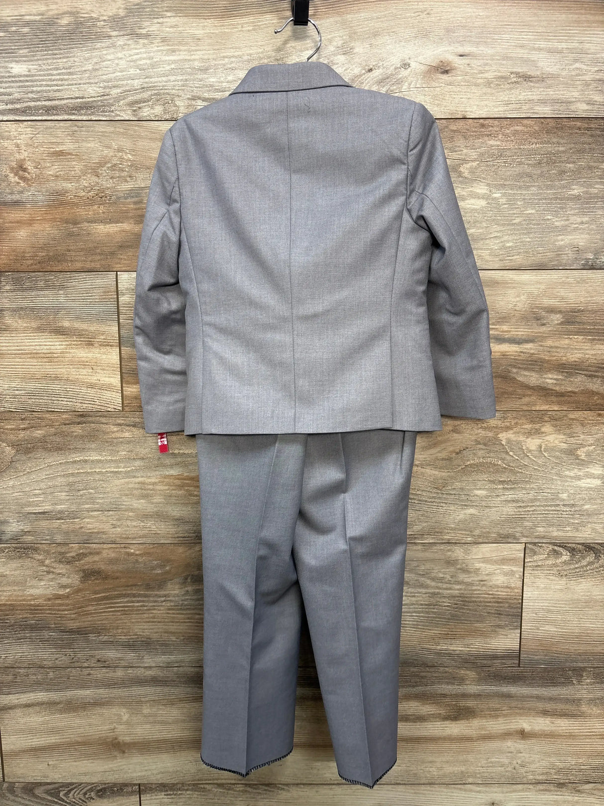 Back view of grey toddler 3-piece slim-fit suit showing jacket back seams and creased pants on wood background