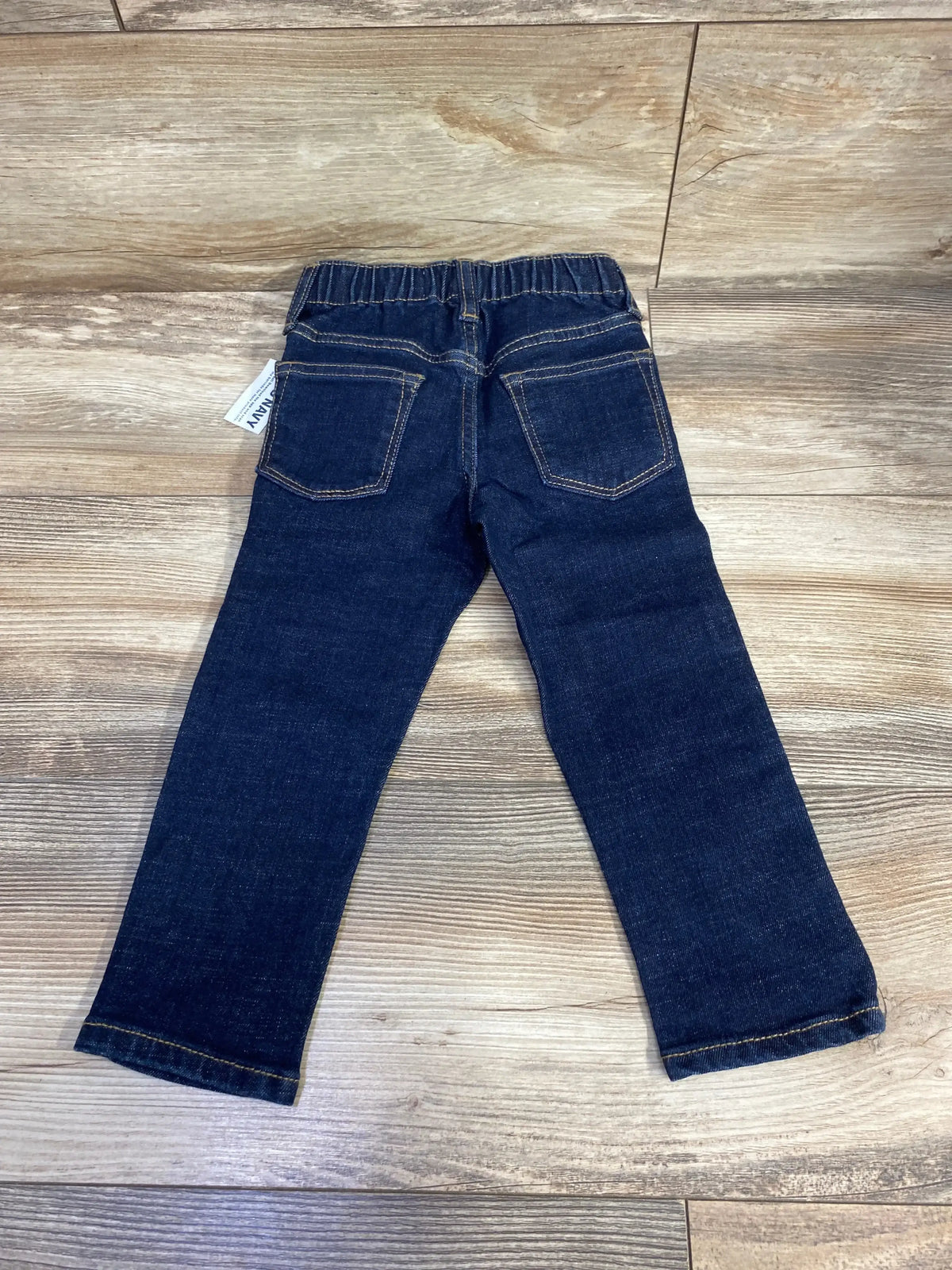 Dark wash toddler jeans with elastic waistband and back pockets on wood floor