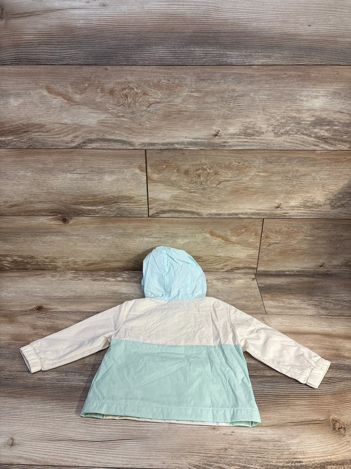Baby mint and white hooded raincoat on wooden floor