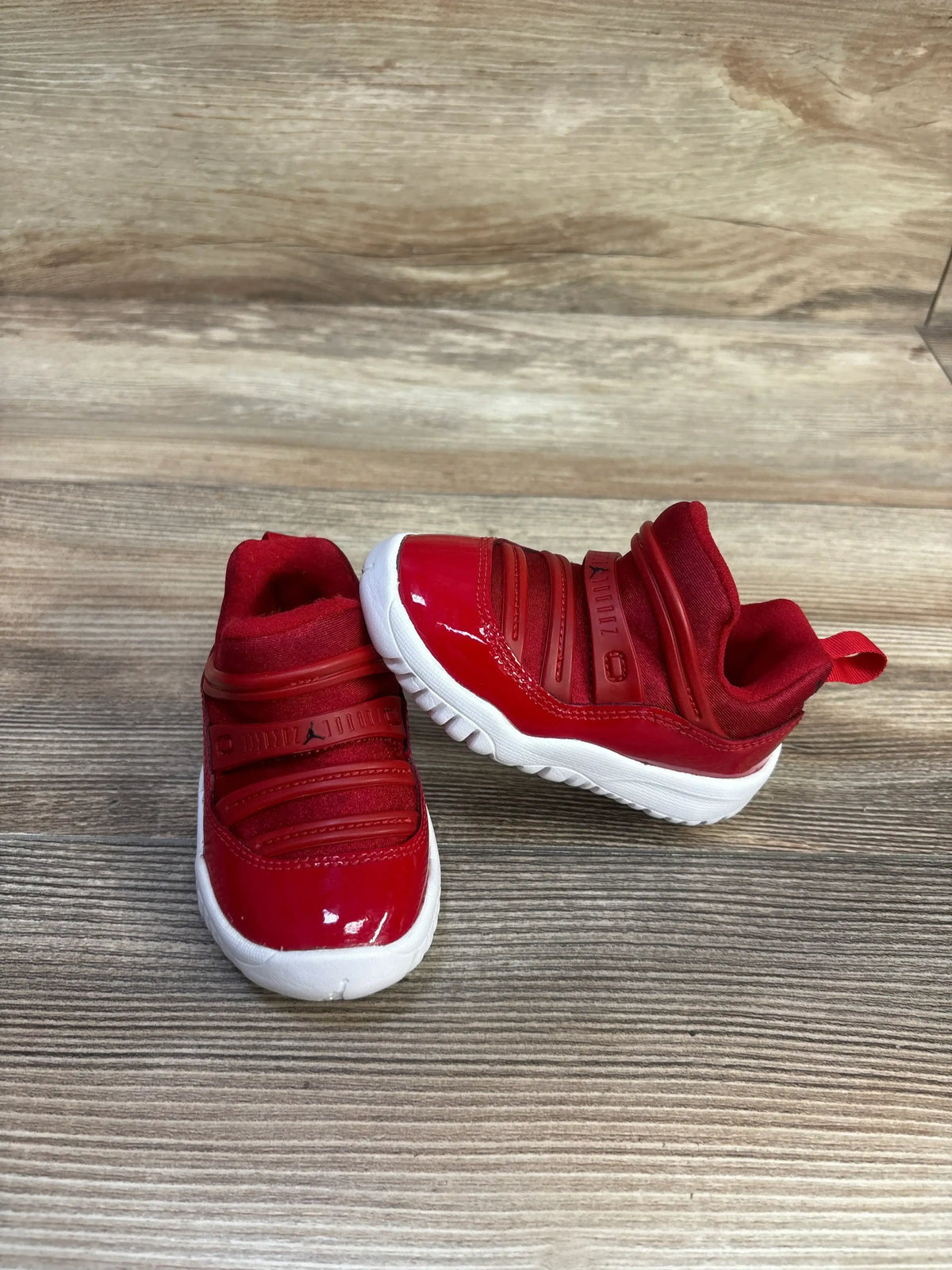 Angled view of Air Jordan 11 Retro Little Flex TD Gym Red sneakers showing red uppers, white soles, and slip on closure