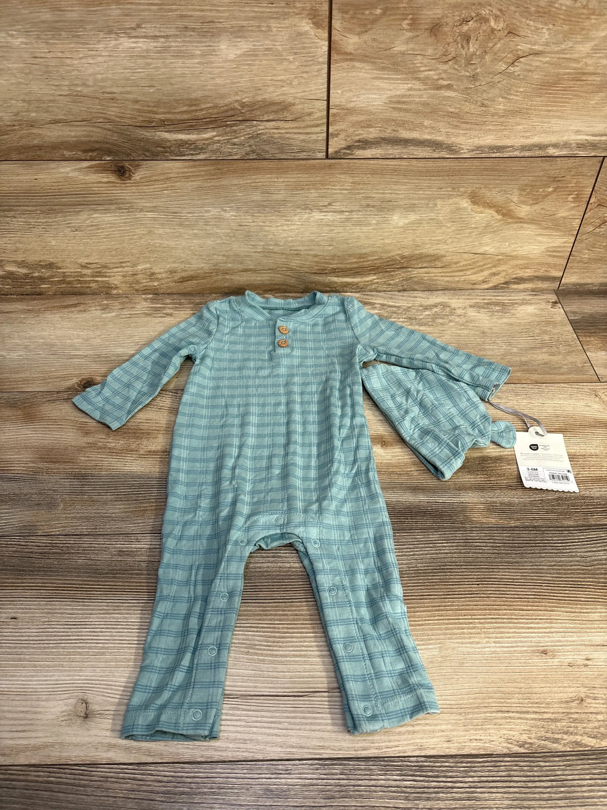Front view of blue jacquard striped romper and matching hat showcasing long sleeves and crotch snaps with a wood-grain background