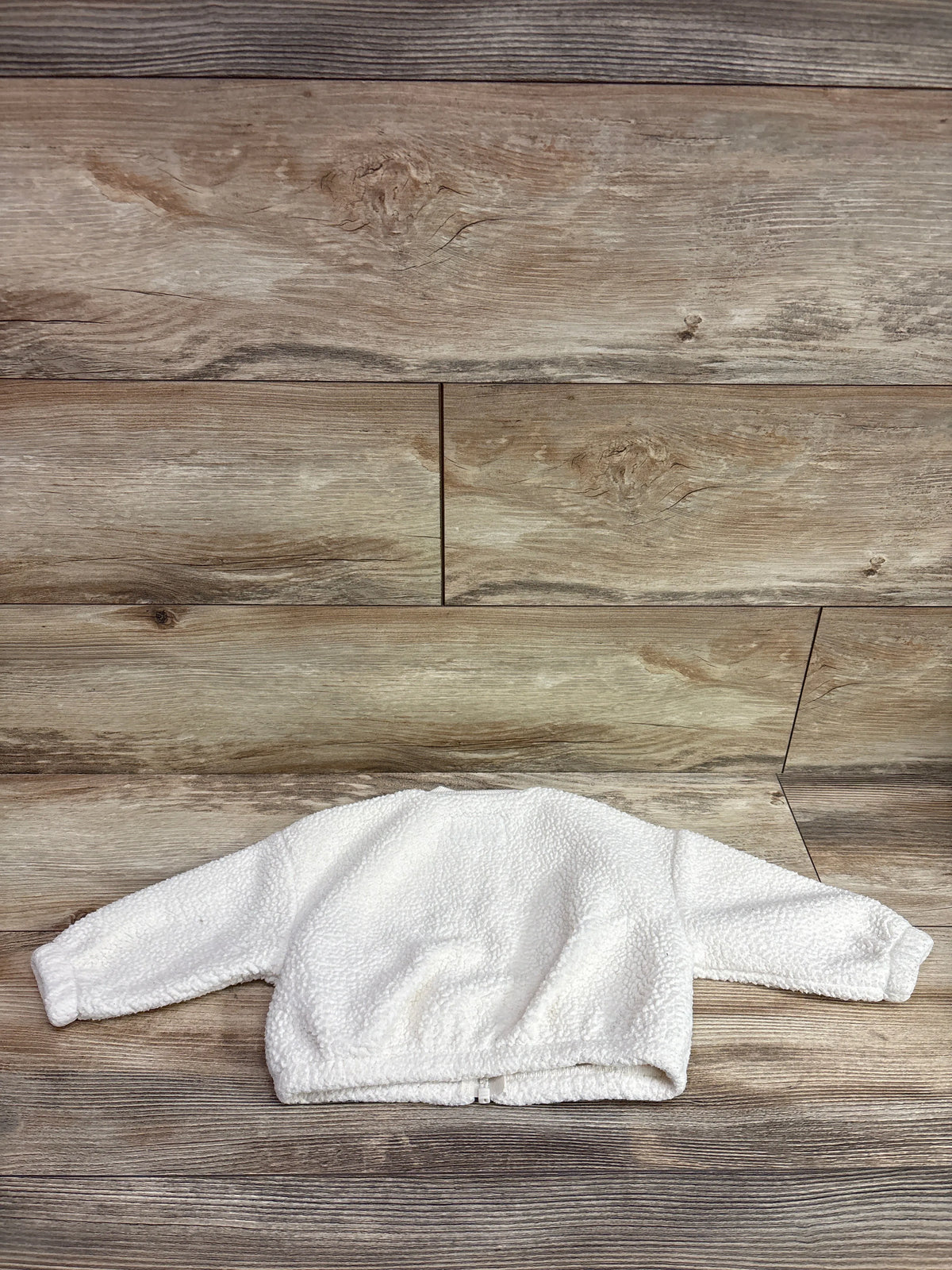 Ivory sherpa jacket for baby size 12m displayed against a wooden background.