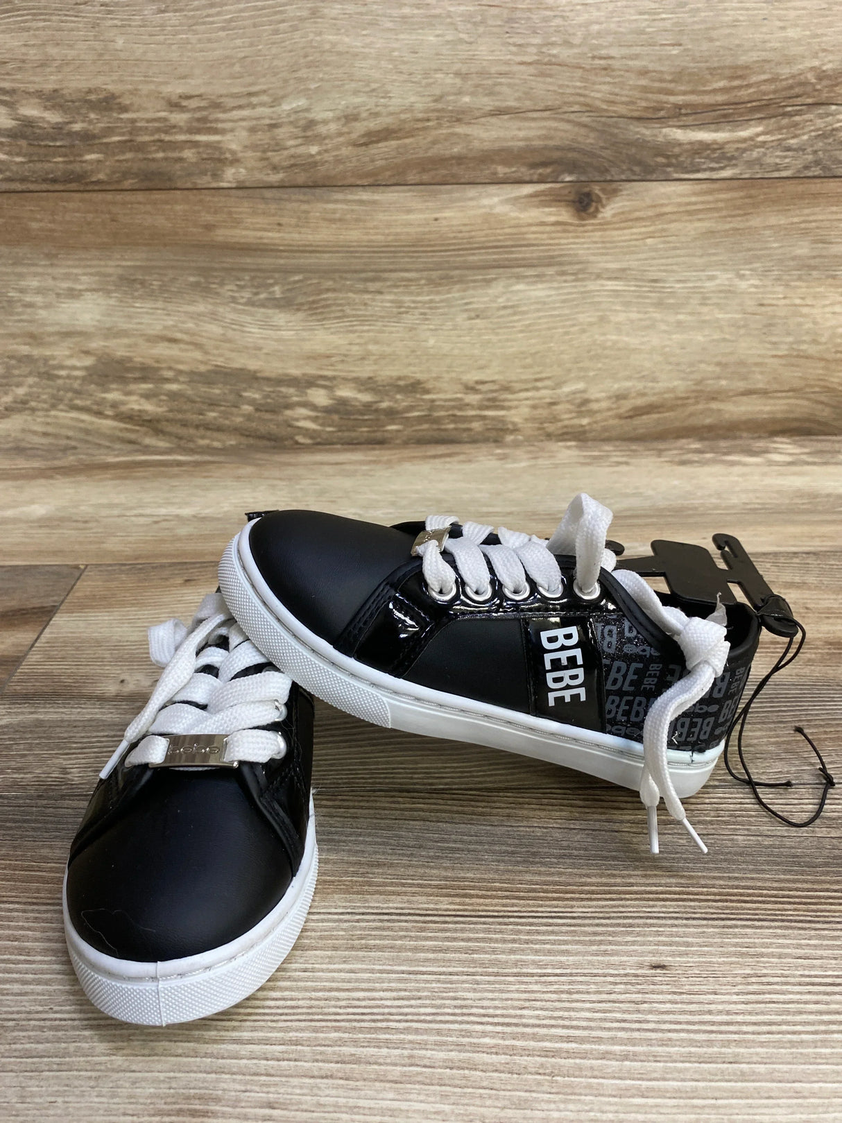 Black BEBE sneakers with white laces on wood floor, fashion shoes with logo detail